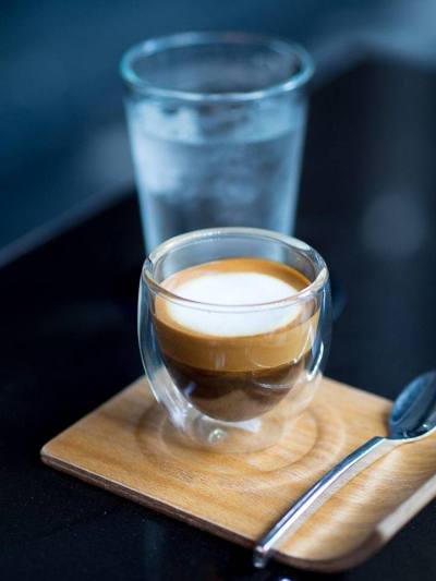 A caffé macchiato with a glass of water at Impresso Espresso Bar in Chiang Mai, Thailand