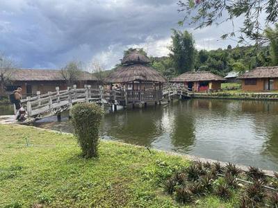 A bridge in the Santichon Chinese village of Pai, Thailand. A river is seen under the bridge with traditional Chinese structures around.