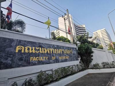 ป้ายคณะแพทยศาสตร์ มหาวิทยาลัยเชียงใหม่ โดยมีอาคารสุจิณโณอยู่เป็นพื้นหลัง