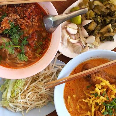 Two types of khao soi are shown here: top left is khao soi Mae Sai (with pork, and no coconut milk) and bottom right is khao soi kai (chicken, with coconut…