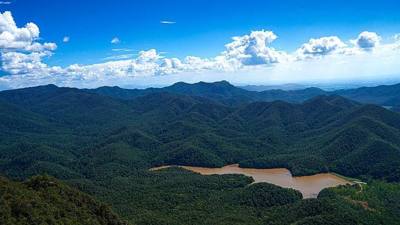 Panoramic view of forested mountain ranges and a reservoir from Doi Nang Mo, a viewpoint in Mae Takhrai National Park, Chiang Mai, Thailand.