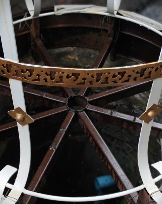 An old well under an iron-spoked cover and a white frame