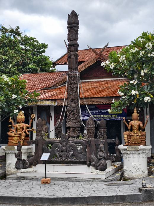 A carved wooden pillar shrine with four-armed guardians at Ban Tawai's craft centre