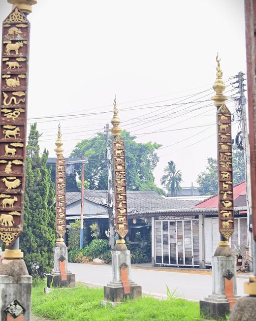 Carved zodiac posts topped with gilt finials along a village road