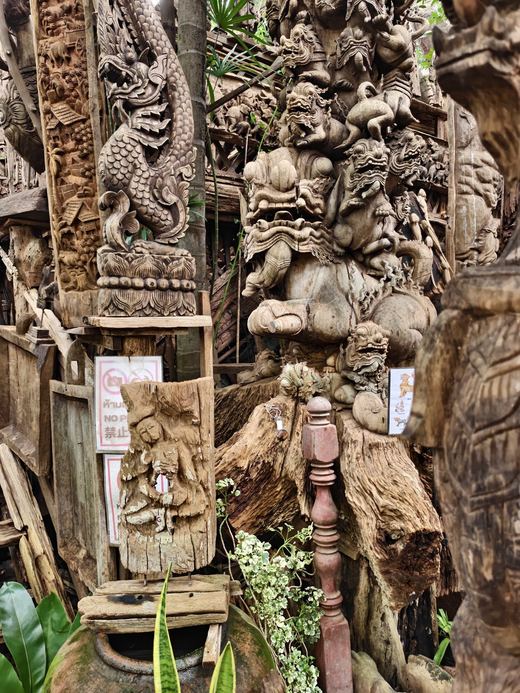 A dragon post and guardian figures packed together at Ban Tipmanee