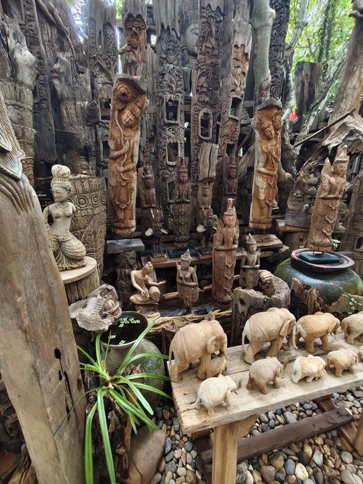 Carved elephants on a bench before a wall of standing figures