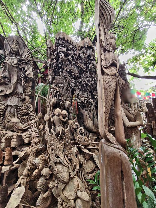 A great carved panel of figures and leaves under the trees