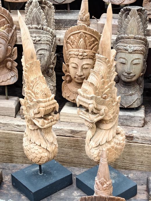 Two carved naga heads on stands before crowned heads