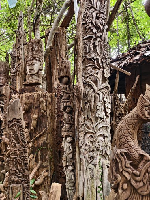 Carved teak pillars with faces and flowers at Ban Tipmanee