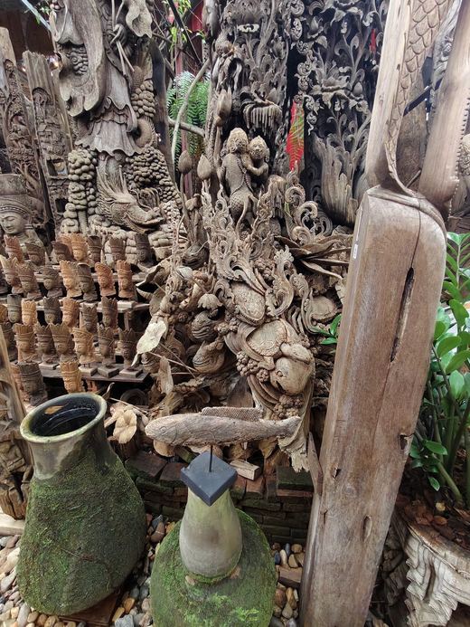Rows of small carved figures behind a mossy jar