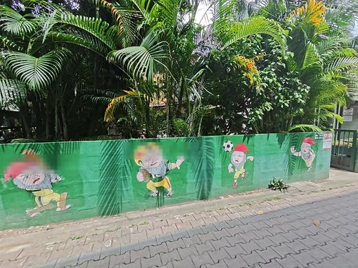 A painted wall of cartoon gnomes playing football along a lane
