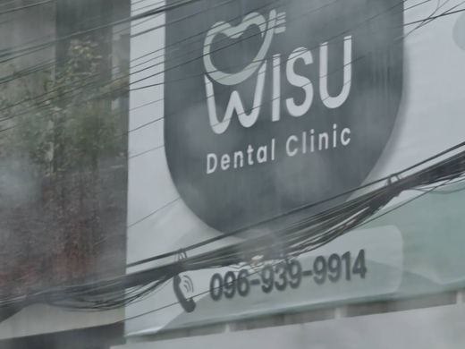 WISU Dental Clinic's sign behind the street wires, 096-939-9914
