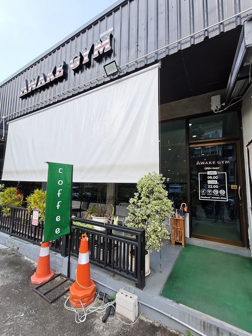 Awake Gym's door: 'coffee' flag, potted bonsai, opening hours on the glass