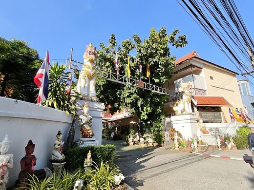 Wat Loi Khro's gate: white singha, guardian figures, flags, the lane in