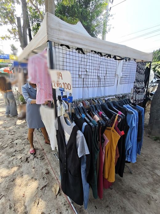 A clothes rack of shirts and dresses, price card 59 or 2 for 100 baht