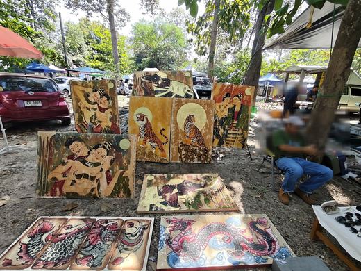 Lanna-style paintings laid on the ground: tigers, dragons, an embracing couple