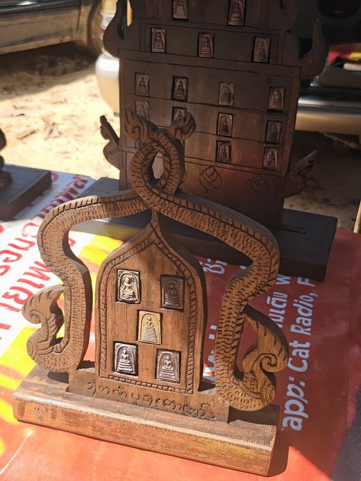 A wooden amulet board with naga curls and five small amulets set in