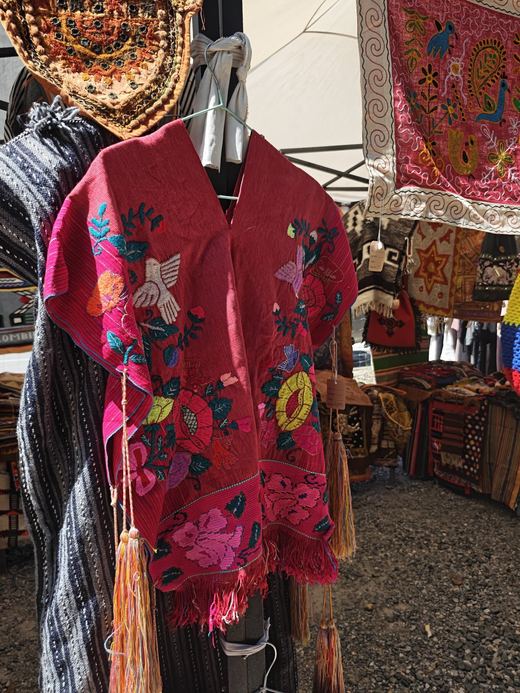 A red embroidered shawl hung among hill-tribe textiles
