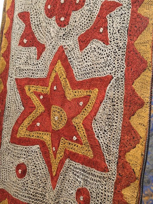 Close-up: a cream embroidery with a red and gold star