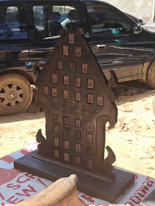 A tall wooden amulet board with rows of small amulets