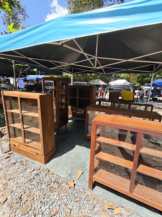 Teak display cabinets for sale under a blue awning