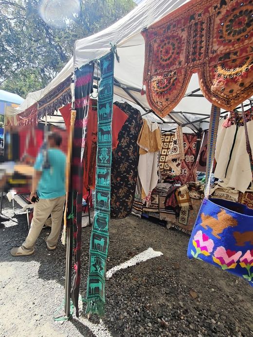 Woven runners with animal figures hang at a textile stall