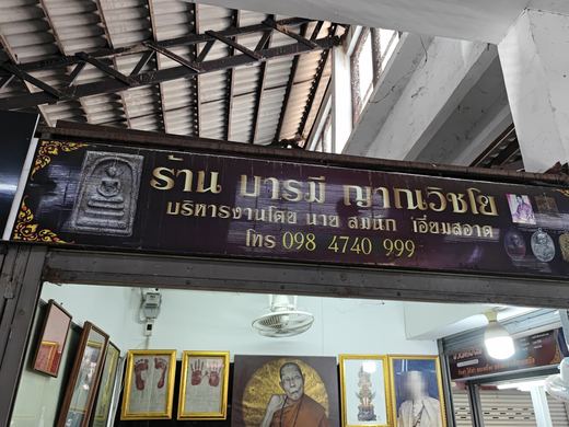 Barami Yanwichayo's sign over framed amulets and monk portraits