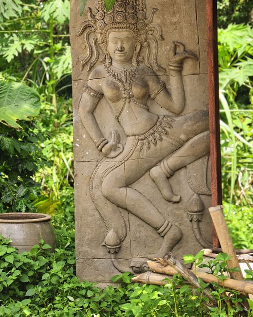A dancing apsara relief on a clay pillar among the leaves