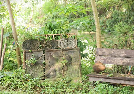 Clay relief panels and a wooden bench in a garden at Chiang Din