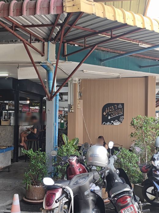 Mahaniyom Coffee's sign on a slatted wall, motorbikes parked in front