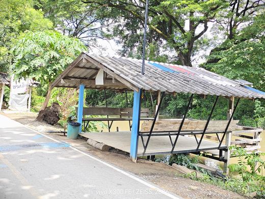 A roadside sala with a blue post, a children-crossing banner beyond