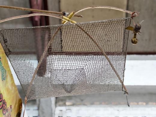 A woven fish trap hung from the market roof