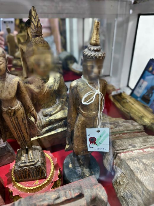 Gilded standing Buddha images in a glass case, a price tag tied on