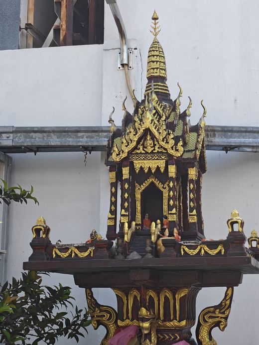 A gilded spirit house on the wall outside Kitcha Dental