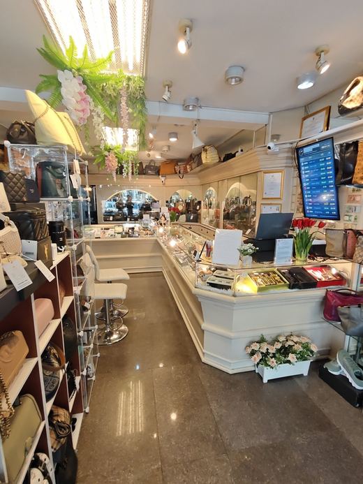 Inside Laila's: glass counters, shelves of pre-owned handbags, a rate screen