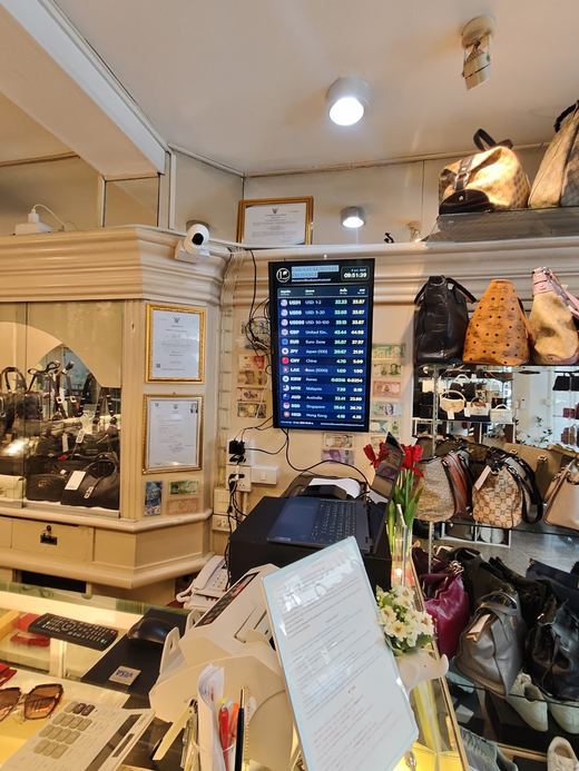 Laila's exchange counter with the rate screen and handbags behind