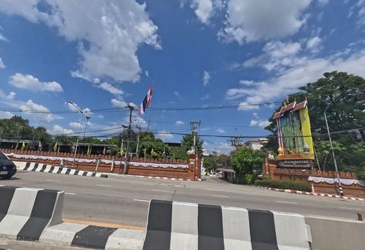 Gate of Provincial Police Region 5, with a red brick wall, a Thai flag and a royal portrait