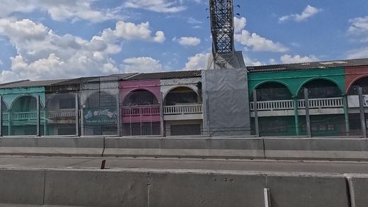 Faded pastel arcaded shophouse row seen from the elevated highway
