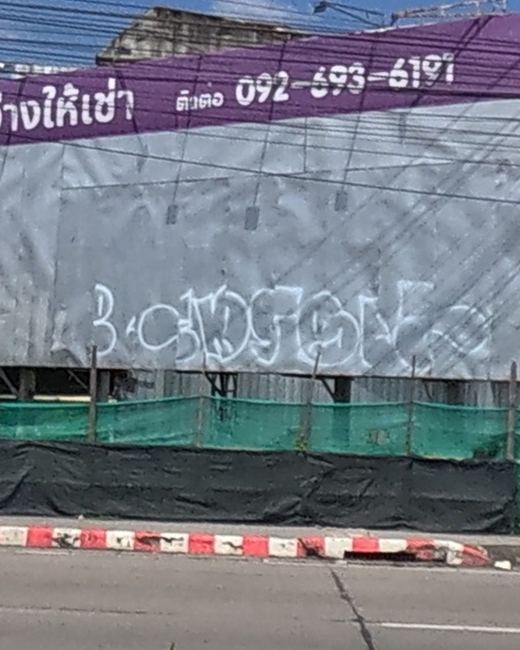 White spray tag on a blank grey billboard face