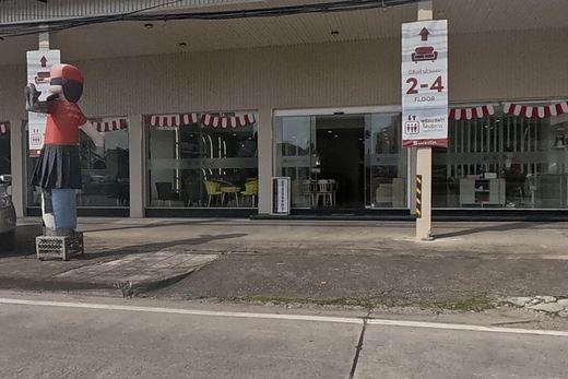 Suwit Furniture Baanma's full frontage is clearly signed, with a pickup truck and a mascot figure out front.