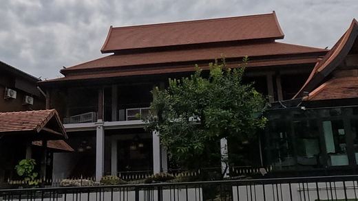 Lanna teak house behind iron fence