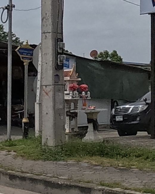 A roadside shrine with offerings by a loan-office pole