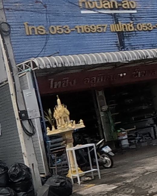 Gold spirit house on a pillar outside a shophouse