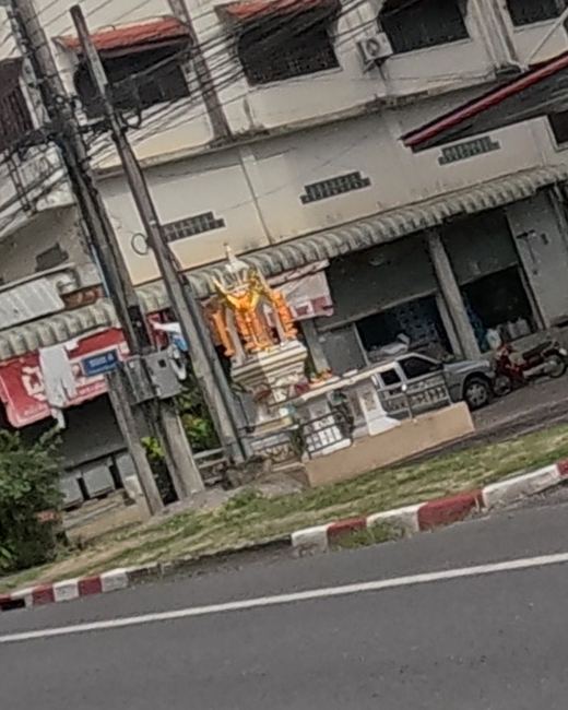 Gold spirit house under a shop arcade