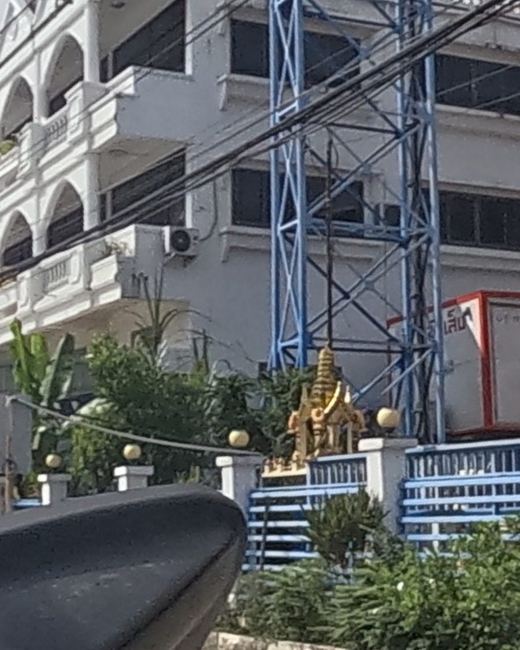Golden spirit house on a machinery yard wall