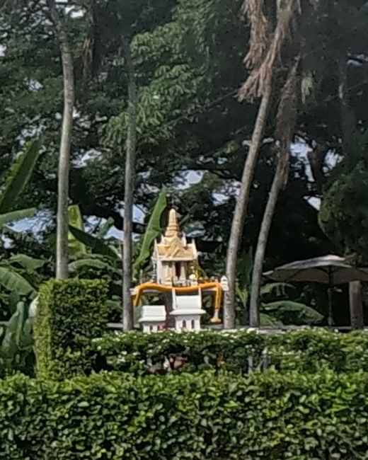 Small gold spirit house glimpsed through trees
