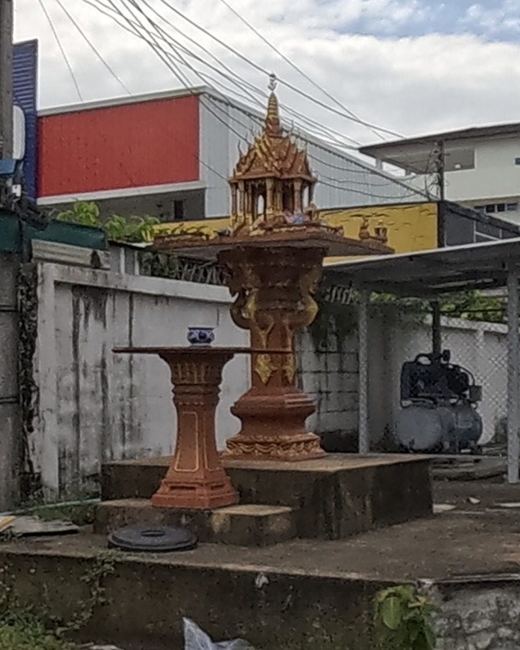 Golden spirit house and offering table on a street corner