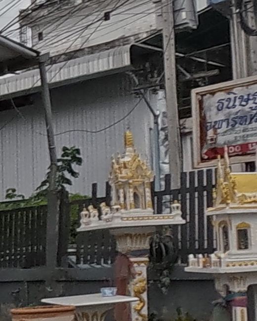 Gold-and-white spirit house on a naga pedestal