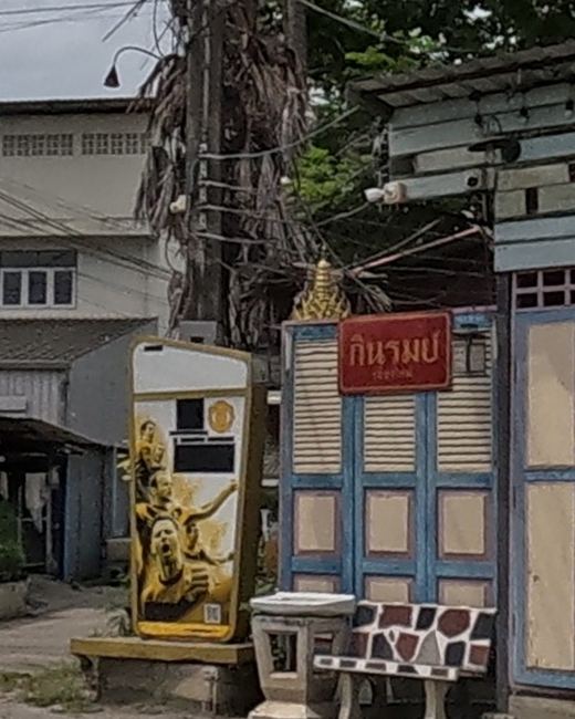 A small gold spirit house by a bar entrance