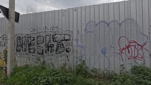Bold black tag with red and blue scribble tags on a metal fence